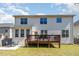 View of backyard featuring a wooden deck, patio with outdoor dining set, and well-maintained lawn at 3557 S Beaver Ln, Raleigh, NC 27604