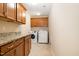 Modern laundry room with wood cabinets, granite counters, tile floors, and washer/dryer at 3557 S Beaver Ln, Raleigh, NC 27604
