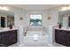 Luxurious soaking tub in a well-lit bathroom, featuring double sinks and views of the outdoors at 4026 Overcup Oak Ln, Cary, NC 27519