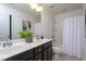Bright bathroom featuring double sinks, modern fixtures, framed mirror, and shower-tub combo with white shower curtain at 4026 Overcup Oak Ln, Cary, NC 27519