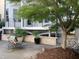 Brick patio area with a fire pit, chair, decorative stone wall, and a beautiful tree at 4026 Overcup Oak Ln, Cary, NC 27519