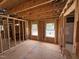 Unfinished living room showing exposed studs, subfloor, and rough openings for windows at 452 Duncan Creek Rd # 156, Lillington, NC 27546