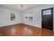 Bright living room featuring hardwood floors, two windows, modern light fixture, and freshly painted walls at 5121 Leesville Rd, Durham, NC 27703