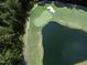 An aerial view shows the golf course bordering a pond with lush green trees at 55 Glasgow, Rocky Mount, NC 27804