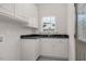 Bright laundry room featuring white cabinets, a black countertop, and natural light from a window at 55 Glasgow, Rocky Mount, NC 27804