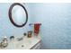 Charming bathroom featuring a vanity sink, round mirror, and blue patterned wallpaper at 5932 Whitebud Dr, Raleigh, NC 27609