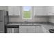 Bright, efficient kitchen with stainless dishwasher and sink, granite counters, and white cabinets at 65 Crow Field St, Roxboro, NC 27574