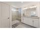 Bright bathroom featuring double sinks, granite countertops, a glass shower, and tiled floors at 6926 Leesville Rd, Raleigh, NC 27613