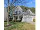 Charming two-story home boasts gray siding, black shutters, lush landscaping, and an attached two-car garage at 7707 Oak Marsh Dr, Raleigh, NC 27616