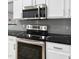 Kitchen features stainless steel appliances, black marble countertops, gray subway tile backsplash, and white cabinets at 7707 Oak Marsh Dr, Raleigh, NC 27616