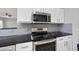 Kitchen features stainless steel appliances, black marble countertops, gray subway tile backsplash, and white cabinets at 7707 Oak Marsh Dr, Raleigh, NC 27616