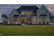 Stunning two-story home with craftsman style architecture and a manicured front lawn at twilight at 8005 Woodcross Way, Wake Forest, NC 27587