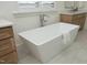 A modern soaking tub in a bathroom with stone tile floors & natural wood cabinets creates a relaxing oasis at 8005 Woodcross Way, Wake Forest, NC 27587