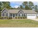 Close up of a charming home with stone accents, gray siding, an oval front door, and a manicured lawn at 808 Cross Link Dr, Angier, NC 27501