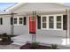 A covered front porch with black iron supports and a red front door at 8215 S Nc 119 Hwy, Mebane, NC 27302