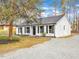 View of the house showing the white brick, black shutters and gravel driveway with a tree in the foreground at 1017 E Club Blvd, Durham, NC 27704