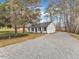Gravel driveway showing the home's white brick, black shutters, a well-manicured lawn, and tree at 1017 E Club Blvd, Durham, NC 27704