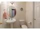 Well-lit powder room with pedestal sink, toilet, decorative mirror, and a neutral color palette at 106 Madison Square Ln, Cary, NC 27513