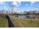 A scenic backyard pond surrounded by lush greenery and a fence, offering a tranquil view at 1295 Kerr St, Burlington, NC 27215