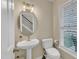 Well-lit half bath with pedestal sink, round mirror, and white fixtures creating a clean and simple design at 1320 Rushing Creek Pkwy, Raleigh, NC 27610