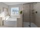 A bathroom showcasing a soaking tub under a window, and a glass door walk-in shower with tiled surround at 1824 Longmont Dr, Wake Forest, NC 27587