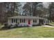 Charming single-story home with a well-manicured lawn, painted brick, and a vibrant red front door at 221 Lane Of Tristram, Garner, NC 27529