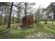 View of a wooden shed in a backyard with green grass and large trees at 221 Lane Of Tristram, Garner, NC 27529