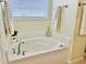 Cozy bathroom featuring a corner tub with a view from the window and white tile at 225 Beckwith Ave, Clayton, NC 27527