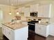 Modern kitchen features white cabinets, granite countertops, stainless steel appliances, and an island with pendant lights at 225 Beckwith Ave, Clayton, NC 27527