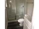 Compact bathroom featuring a glass-enclosed shower, toilet, and white vanity with silver fixtures at 2600 Fayetteville St, Durham, NC 27707
