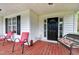 Inviting front porch with seating, featuring bright red chairs and a charming wicker bench with floral cushions at 2709 White Rail Dr, Fuquay Varina, NC 27526