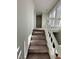 Carpeted staircase with white wooden railing and sunlit landing at 306 Smoketree Way, Louisburg, NC 27549