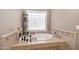 Relaxing bathroom featuring a large tub surrounded by tile and a window for natural light at 316 Pebble Beach Dr, Mebane, NC 27302