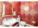 Stylish powder room with textured red wallpaper, elegant sink, and gold accents offers a touch of luxury at 316 Pebble Beach Dr, Mebane, NC 27302