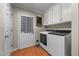A well-lit laundry room featuring a modern washer and dryer, upper cabinets, and access to the backyard at 347 Cook Rd, Elon, NC 27244