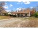 Single-story residence, featuring a covered front porch, trimmed bushes, and a gravel drive on a sunny day at 3490 Old Buies Creek Rd, Angier, NC 27501
