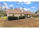 Tan-sided home, showcasing neat shrubbery, a peaked roof, and a welcoming front porch under a partly cloudy sky at 3490 Old Buies Creek Rd, Angier, NC 27501