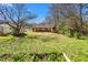 A charming brick home with a lush backyard, accented by mature trees, and a weathered storage shed at 369 Albany St, Burlington, NC 27215