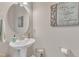 Stylish half bathroom featuring a pedestal sink, decorative mirror, and neutral decor at 3925 Massey Pointe Ct, Raleigh, NC 27616