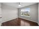 A cozy bedroom with hardwood floors, a ceiling fan, and a window with neighborhood views at 4044 Dunkirk Dr, Burlington, NC 27215