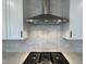 Close-up of a modern kitchen range hood, with light gray subway tiles, and a black cooktop at 4310 Emeline Way # 18, Fuquay Varina, NC 27526