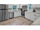 Well-lit kitchen featuring stainless steel appliances, white cabinets, and modern flooring at 4408 Poplar Dr, Raleigh, NC 27610