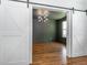 View of a modern living room with hardwood floors, updated lighting, dark paint and barn door access at 5347 Cypress Ln, Raleigh, NC 27609