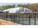 A fenced tennis court area with a large white dome in the background for indoor play at 5347 Cypress Ln, Raleigh, NC 27609