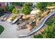 Inviting community park showcasing modern slides integrated into natural stone landscaping and lush greenery at 600 Hedrick Ridge Road # 112, Cary, NC 27519