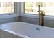 Close-up of a soaking tub with gold fixtures and a view of the trees at 73 Clyde Pearce Rd, Zebulon, NC 27597
