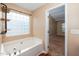 Bathroom featuring a large soaking tub, privacy window, and doorway to bedroom at 1 Serenity Ct, Durham, NC 27704
