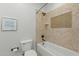 Tiled bathroom featuring a shower-tub with a niche, a toilet and a motivational 