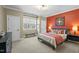 Bedroom with an orange accent wall, large window and a bed with colorful pillows and a nightstand at 1009 High Trail Ct, Wake Forest, NC 27587