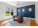 Stylish home office featuring blue accent wall, large window with natural light, and hardwood floors at 1009 High Trail Ct, Wake Forest, NC 27587